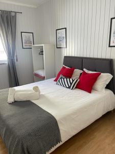 a large bed with red and white pillows on it at West Coast Peniche in Peniche