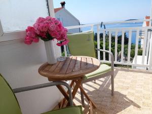 a vase of pink flowers on a table on a balcony at Apartments Vucetic in Hvar