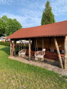 einem Holzpavillon mit 2 Stühlen und einer Schaukel in der Unterkunft Domki u Wiesi in Giżycko