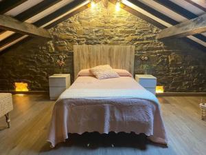a bedroom with a large bed in a stone wall at POSADA de BUSTIELLO in Mieres