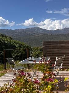 a table and chairs on a deck with mountains in the background at Orizzonte montagna in Figari