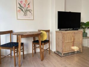 Una sala de estar con una mesa, un televisor y sillas. en Beach Bliss, en Noordwijk