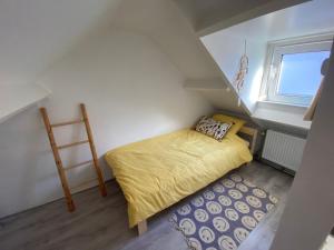 Un dormitorio pequeño con una cama amarilla y una escalera. en Beach Bliss, en Noordwijk