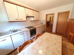 uma cozinha com uma mesa, um lavatório e armários em Apartmaji Zupanc Ivanka em Bohinj