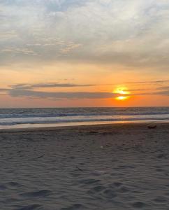 um pôr-do-sol numa praia com o oceano em Suites Playas em Data de Villamil