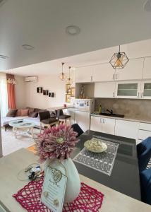 Apartman Kovacevic في بار: مطبخ وغرفة معيشة مع طاولة مع مزهرية