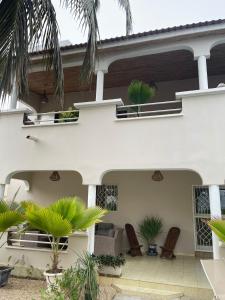 une maison blanche avec des palmiers devant elle dans l'établissement Villa Ngorè Saly, à Saly Portudal