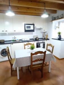 a kitchen with a table and chairs and a kitchen with white cabinets at El Rinconin de Degu in San Juan de Parres