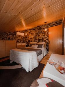 ein Schlafzimmer mit einem Bett und einer Steinmauer in der Unterkunft A Casinha do Cantinho in Arouca