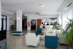 a lobby with white and blue furniture and people at Bikini Hotel in Vieste