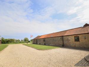 an old brick building with a flag flying in the sky at Tawny Cottage in Alford