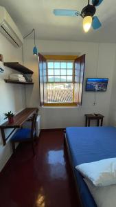 um quarto com uma cama, uma secretária e uma janela em Pousada Aquarium Centro Histórico em Paraty