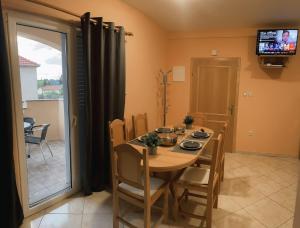 a dining room with a table and chairs and a television at Adriatic Oasis Apartments in Preko