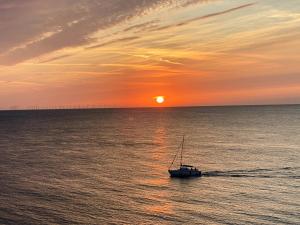 een boot in de oceaan met de zonsondergang op de achtergrond bij Flintback Cottage 3 Bedroom Ensuite Great Location in Kent
