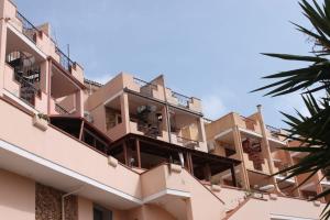 um edifício de apartamentos com varandas e palmeiras em La Perla nel Blu em Villasimius
