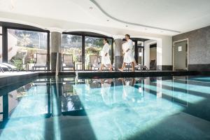 Dois homens de fato branco a andar à beira de uma piscina. em Hotel Seefelderhof em Seefeld no Tirol