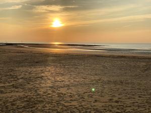 a sunset on the beach with a ball in the sand at Flintback Cottage 3 Bedroom Ensuite Great Location in Kent