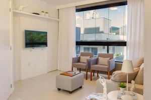 sala de estar con sofá, sillas y ventana grande en Apartamento com Terraço a 300m da Praia em Itapema P1771, en Itapema