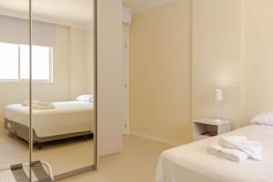 1 dormitorio con 2 camas y espejo en Apartamento com Terraço a 300m da Praia em Itapema P1771, en Itapema