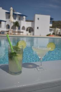a drink sitting on a table next to a pool at Amodari studios on the beach in Plaka