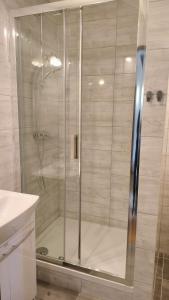 La salle de bains est pourvue d'une douche avec une porte en verre. dans l'établissement Zajazd u Hermanów, à Olsztyn