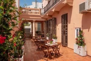 an outdoor patio with tables and chairs and flowers at Antonios Hostal in Sitges
