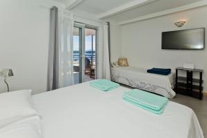 a white bedroom with two beds and a television at Rino in Hvar