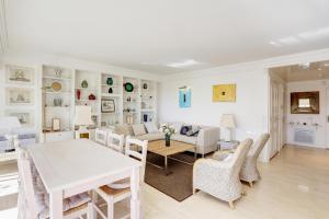 - un salon avec une table et des chaises blanches dans l'établissement Appartement - villa Le Saint Georges avec superbe jardin et vue mer panoramique, à Cannes