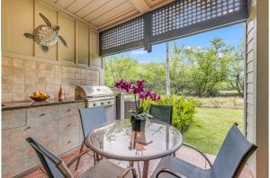 a patio with a table and chairs and a kitchen at Kulalani At Mauna Lani 804 in Waikoloa