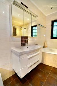 a white bathroom with a sink and a tub and a mirror at Schönbrunn Villa ZM in Vienna