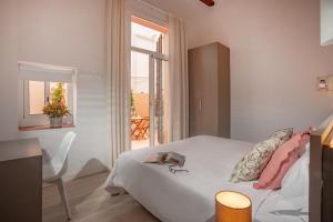 1 dormitorio con cama blanca y ventana en Antonios Hostal, en Sitges