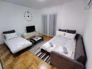 a living room with a couch and a bed and a clock at Apartman MiS Trebinje in Trebinje