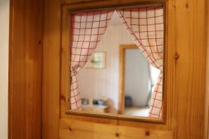 a mirror with a red checked curtain in a room at Aussichtsreich Odenwald in Wald-Michelbach