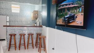 uma cozinha com um bar com bancos e uma televisão em Casa da Lis pé na areia em Morro de São Paulo