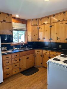 cocina con armarios de madera y horno de fogón blanco en Beautiful Bungalow and Bunk House, Close to Lake en Nordman