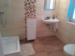 a bathroom with a sink and a toilet and a shower at Vörösmarty Apartman in Dombóvár