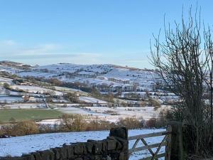 a snow covered hill with a fence and a field at Bank Building Apartments in Barnoldswick