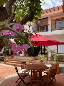 uma mesa e cadeiras com um guarda-sol vermelho e flores em Hotel Villa Teresita em Sáchica