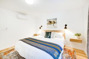 a bedroom with a large white bed with a striped blanket at Peaceful Mendocino Cottage Surrounded By Redwoods in Mendocino