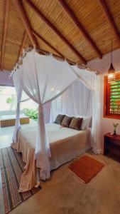 a bedroom with a white bed with a canopy at Vila dos Macacos Trancoso in Trancoso