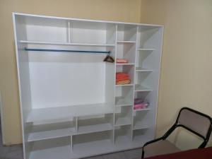 um armário com prateleiras brancas e uma cadeira em Departamento Villa Libertad em Leandro N. Alem