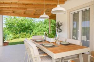 una sala da pranzo con tavolo in legno e sedie bianche di Holiday home Country retreat a Višnjan (Visignano)