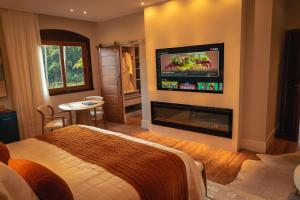 Saison Resort & Spa في إتايبافا: غرفة نوم مع سرير ومدفأة مع تلفزيون