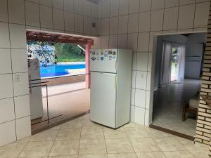 a kitchen with a white refrigerator and a window at Pousada camping Recanto Joanópolis in Joanópolis