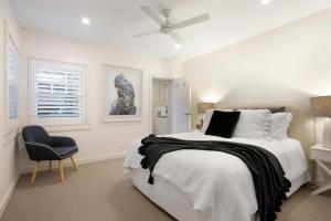 a white bedroom with a bed and a chair at Beach Retreat in Sydney