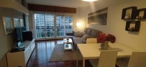 uma sala de estar com um sofá e uma mesa em Moderno y luminoso 2 dormitorios con todas las comodidades en Pontevedra ciudad em Pontevedra