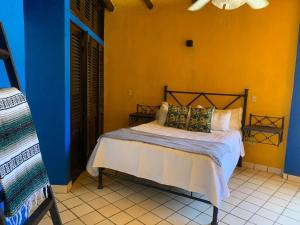 een slaapkamer met een bed in een blauwe en gele muur bij VILLA OASIS in Puerto Vallarta