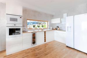 a white kitchen with white appliances and a wooden floor at Hyrna Chata Relaks&SPA in Maniowy