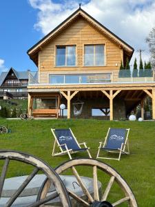 a house with two lawn chairs in front of it at Hyrna Chata Relaks&SPA in Maniowy