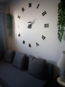 um grande relógio sobre uma parede acima de um sofá em CHAMBRE & SDB PRIVÉE avec piscine en bord de Via Rhona em Sarras
